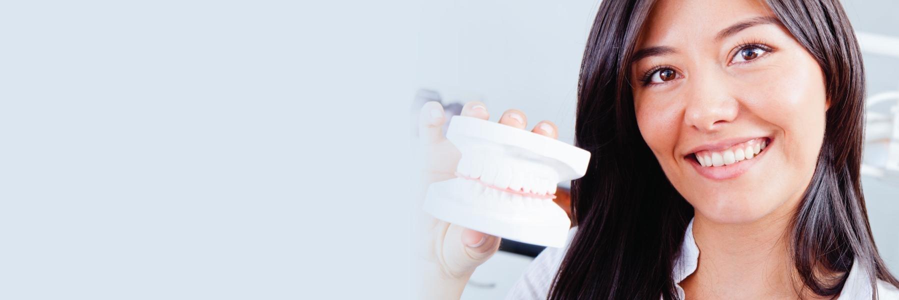 Woman holding up model of teeth | Dental Implants Bonita Springs
