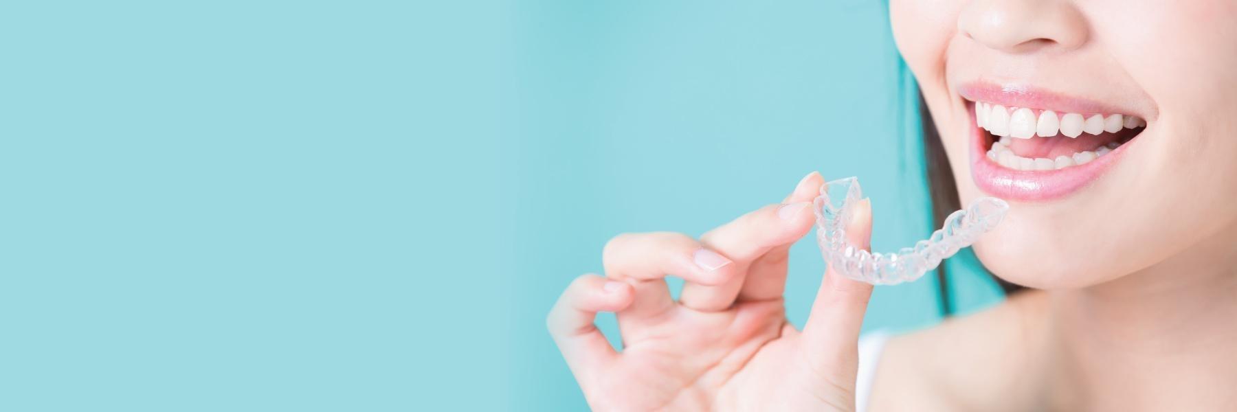 Woman holding up a tray of Invisalign aligners