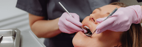 A dentist performs a dental check-up using a mirror and probe.