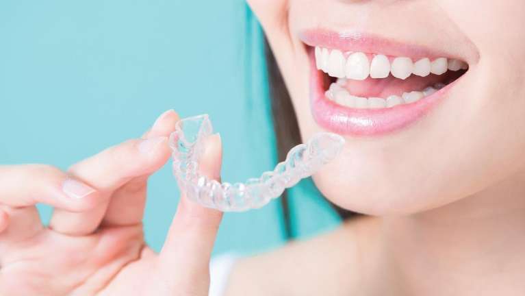 Girl smiling while holding her clear aligners in Bonita Springs FL