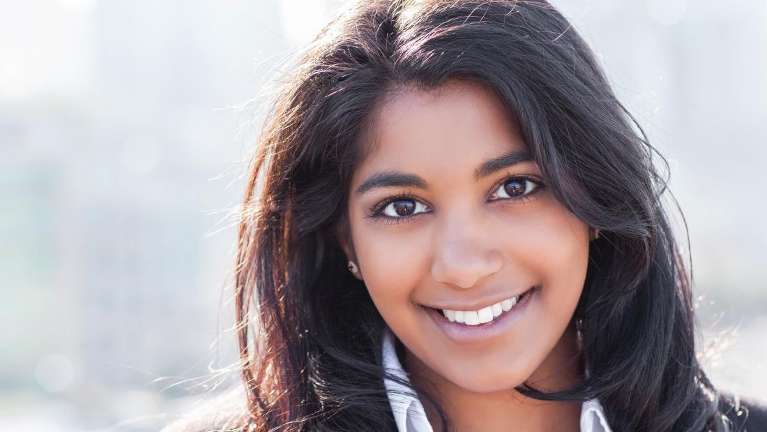 A woman with a broad smile on her face, showing her teeth